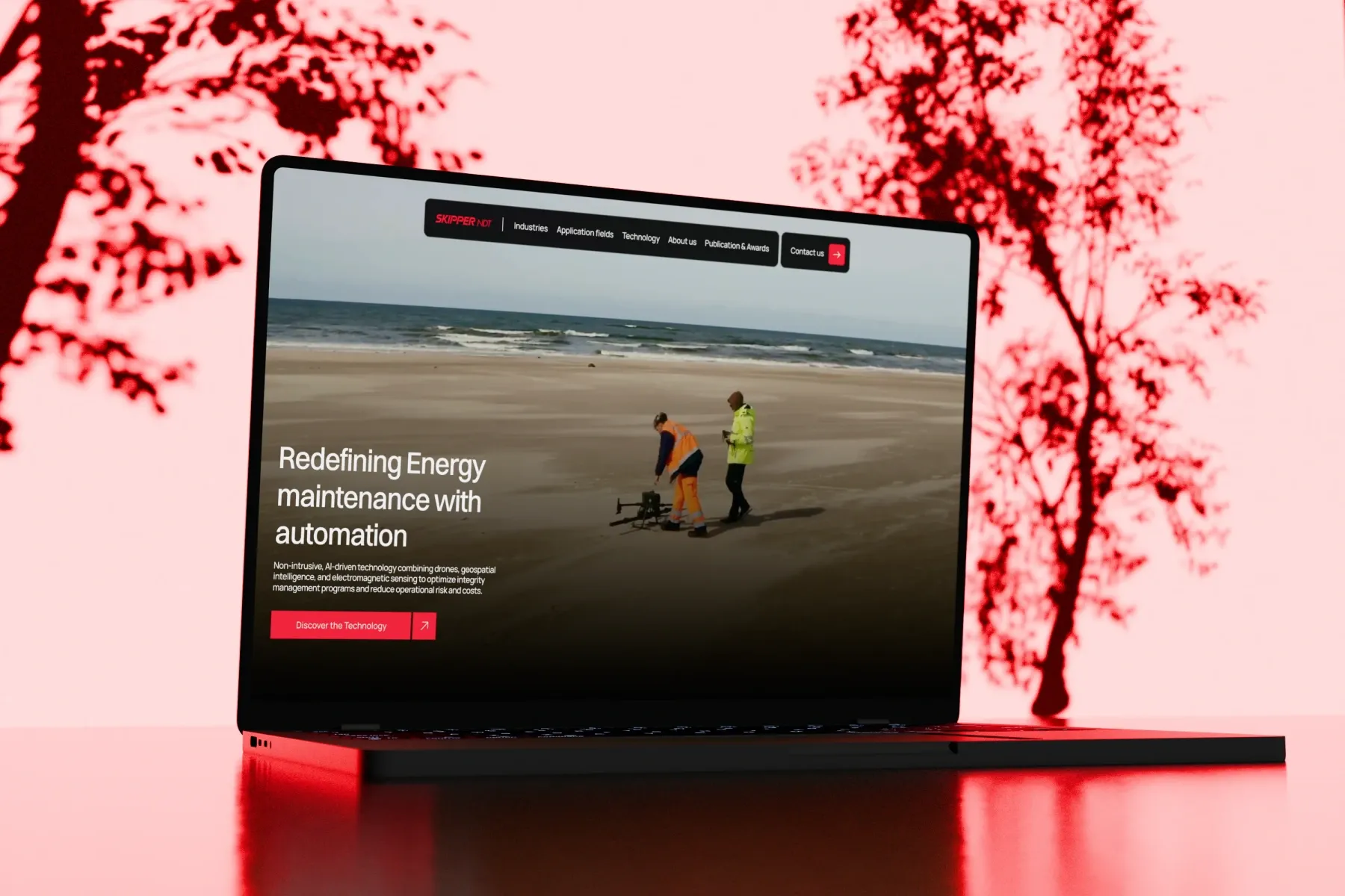 Laptop showing the Skipper NDT website on energy maintenance automation, in a red scene by Junca Studio